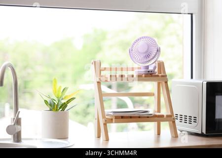 Lilac mini fan on shelf in kitchen Stock Photo