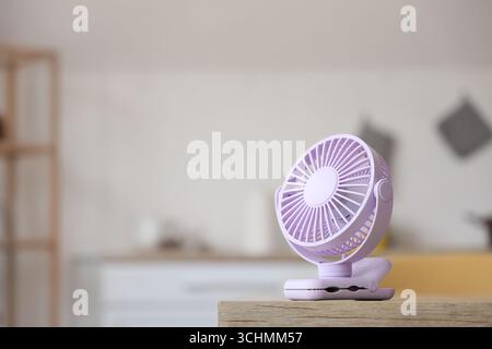 Lilac mini fan on table in kitchen, closeup Stock Photo