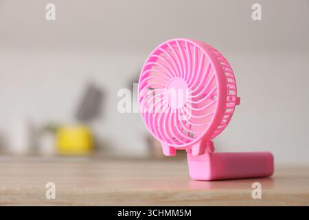 Pink mini fan on table in kitchen, closeup Stock Photo