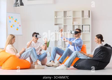 Young colleagues using VR glasses on beanbags in office Stock Photo