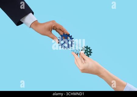 Hands with gears on blue background Stock Photo