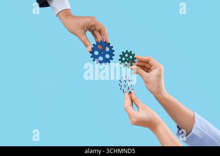 Hands with gears on blue background Stock Photo