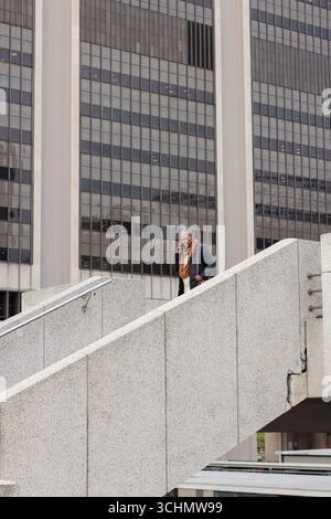 Senior african american woman descending stairs at office tower calling on smartphone Stock Photo