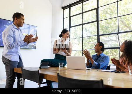 Diverse business team collaborating and applauding during meeting in modern office Stock Photo