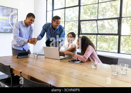 Diverse business team collaborating on laptop in bright office meeting room Stock Photo