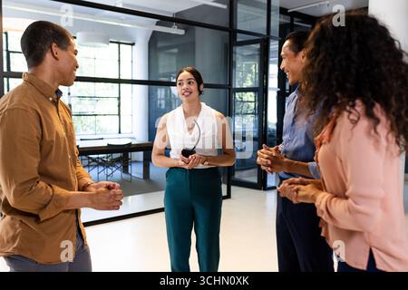 Diverse business team discussing project in modern office, smiling and engaged Stock Photo