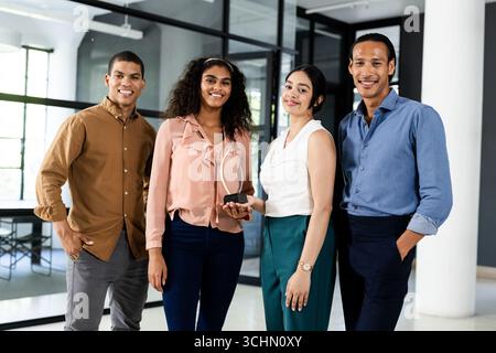 Diverse business team smiling confidently while holding award in modern office Stock Photo