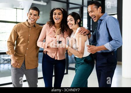 Diverse business team laughing and celebrating success in modern office Stock Photo