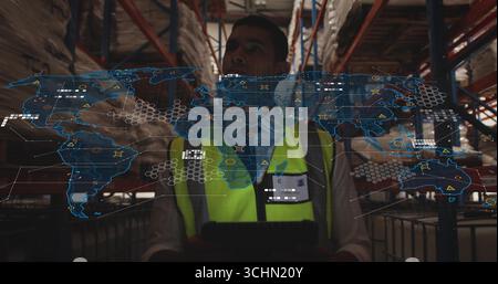 Using tablet hi-vis vest clad worker viewing digital map overlay in warehouse aisle, racks, pallets Stock Photo