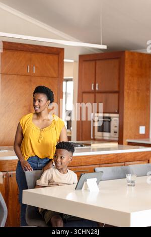 Mother and son smiling while using tablet at home in modern kitchen Stock Photo
