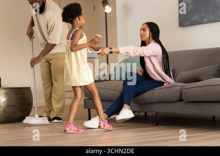 In living room, African American family cleaning, child helping parents with chores Stock Photo