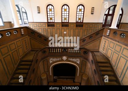 Symmetrical grand staircase with ornate details and arched windows in a historic building. Stock Photo