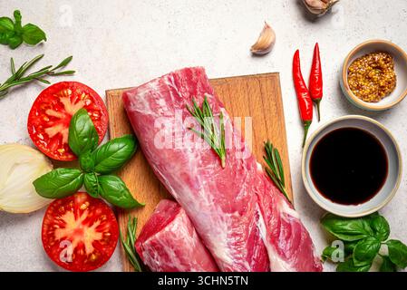Fresh raw beef meat ready to cook. Meat tenderloin with vegetables, herbs and spices on white background, top view. Stock Photo