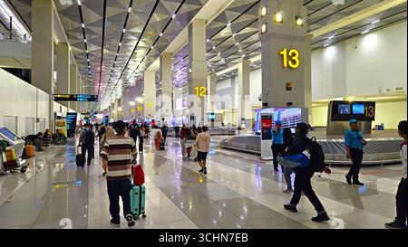 Busy airport terminal with passengers walking in check-in area under bright modern interior. Jakarta, Indonesia - December 17th, 2024 Stock Photo