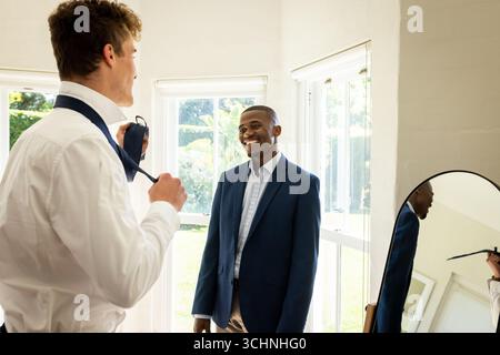 Groom and best man preparing for wedding, adjusting ties and smiling warmly Stock Photo