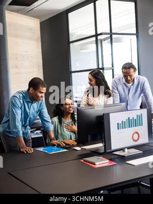 Diverse business team collaborating on project, analyzing data on computer screen, at office Stock Photo