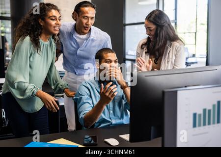 Collaborating on project, diverse team discussing ideas around computer in office Stock Photo