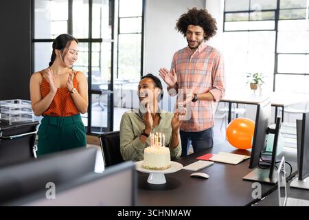 Diverse colleagues celebrating birthday in office with cake and clapping hands Stock Photo