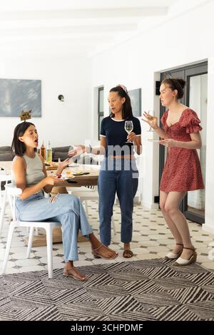 Engaging in animated conversation, three young women enjoy casual gathering at home Stock Photo