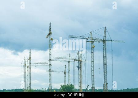 Moscow, Russia, 18.08.2025 Many yellow construction tower cranes stand tall against a cloudy sky. Industrial construction site for urban development p Stock Photo