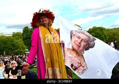 London, UK - 19 September 2022: Grieving woman holds up a giant flag of Queen Elizabeth II in Hyde Park, London, during the Queen's funeral Stock Photo