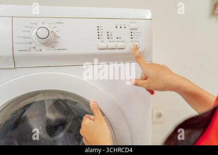 User Engaged in Interaction with a Washing Machines Control Panel for Settings Stock Photo