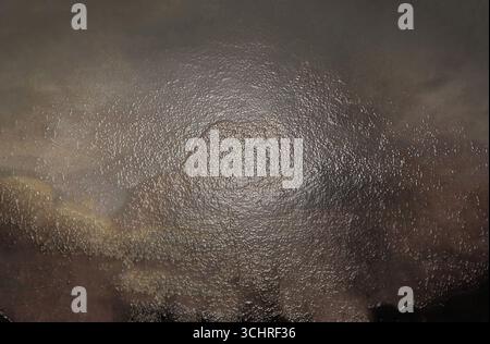Wet asphalt surface reflecting light creating abstract shapes and textures, perfect for backgrounds and design projects Stock Photo