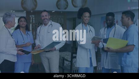 Discussing medical professionals reviewing patient charts in hospital lounge, with stethoscopes Stock Photo