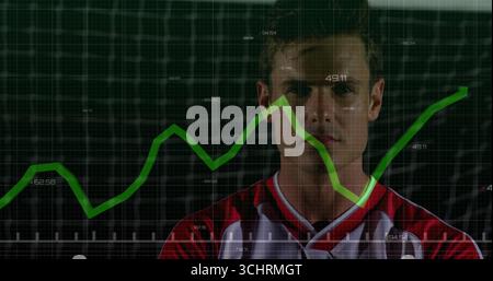 Standing baseball player wearing red and white jersey facing grid wall in studio, with green graph Stock Photo