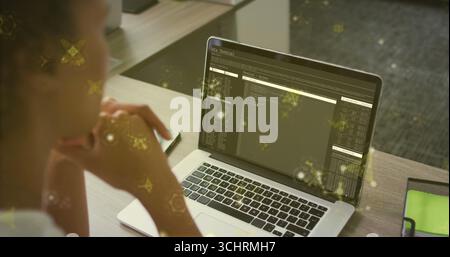 Woman wearing casual top reviewing laptop terminal at office desk, with phone notebook, copy space Stock Photo