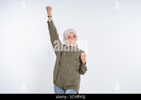 A Cheerful Young Woman Joyfully Celebrating Her Success with a Fist Pump Gesture Stock Photo