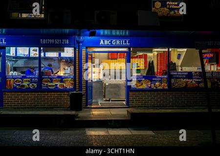 A night time view of a takeaway restaurant in Saffron Walden, Essex, England, with an 'open' sign and food displayed. Stock Photo