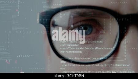 Focusing developer's eye behind black-rimmed glasses at digital interface with code and binary bits Stock Photo