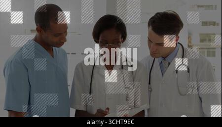 Reviewing healthcare team collaborating in hospital corridor, with stethoscopes and clipboard Stock Photo