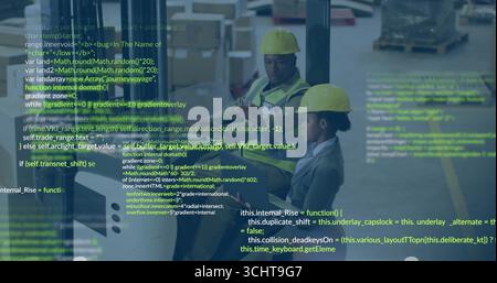 Staff wearing hard hats and safety vests checking tablet data in warehouse, with boxes and pallets Stock Photo
