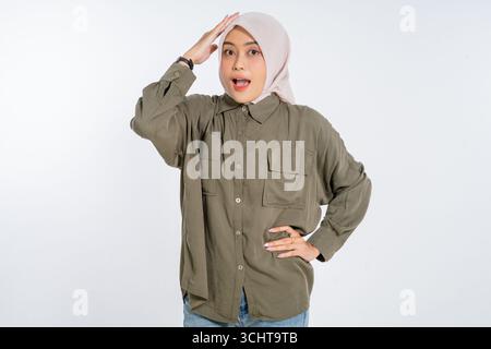 A surprised young woman in a very stylish outfit has her hand placed on her head Stock Photo