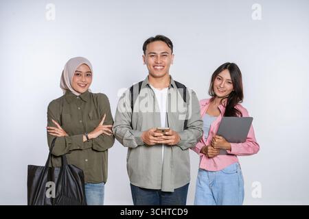 A Diverse Group of Students Smiling Joyfully with Their Gadgets in a Studio Setting Stock Photo