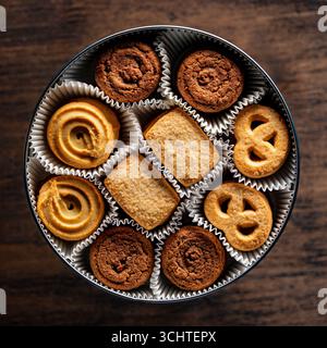 Crispy crumbly shortbread cookies in a round metal box on wooden table, top view, close up Stock Photo