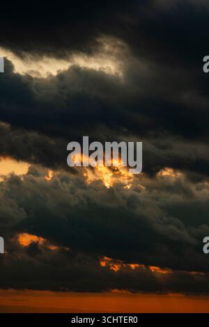 Dark dramatic horizon sky during sunset. Black clouds and setting sun. Evening sunshine background Stock Photo