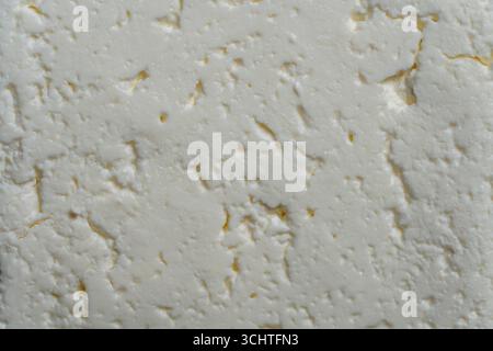 Texture and background of a piece of fresh white cottage cheese, close up, top view. Homemade white cheese from cow's milk Stock Photo
