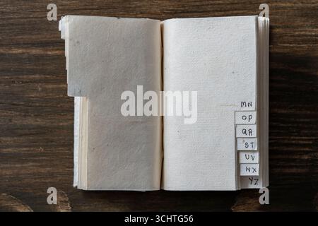 Opened empty vintage book with alphabet on pages on wooden background, space for text, close up, top view, copy space Stock Photo