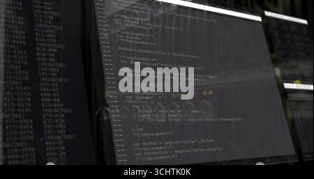 Displaying computer monitor presenting JavaScript code in dimly lit office, with secondary monitor Stock Photo