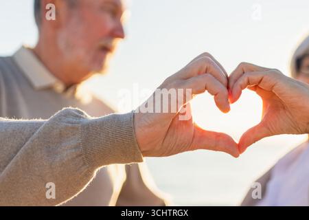 Love heart shape peace. Senior older couple making heart shape with their hands. Adult mature old husband wife showing heart sign. Happy pensioner family. I love you happy valentines day Stock Photo