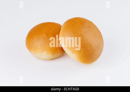 Two fresh golden hamburger buns on white background, ideal for bakery or food packaging design Stock Photo