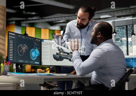 Manager and researcher working together, analyzing turbine components to improve sustainability metrics. Green tech company team leader and coworker modify turbine parts to cut emissions Stock Photo