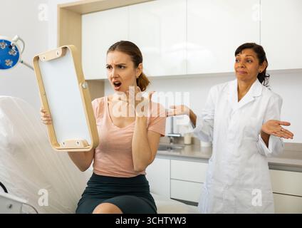 Dissatisfied woman checking result after cosmetology procedure Stock Photo