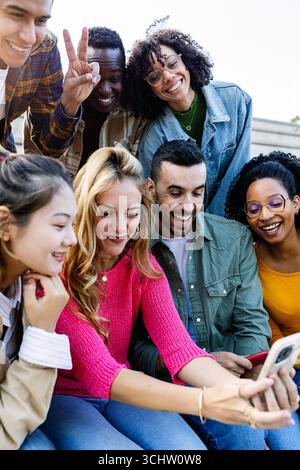 Happy multiracial millennial friends having fun outdoors using mobile phones Stock Photo