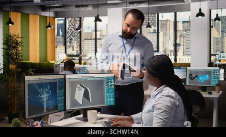 Team of engineers brainstorm upgrades for innovative solar powered device prototype. Research and development office coworkers do trial of portable solar panel gadget to improve efficiency, camera A Stock Photo