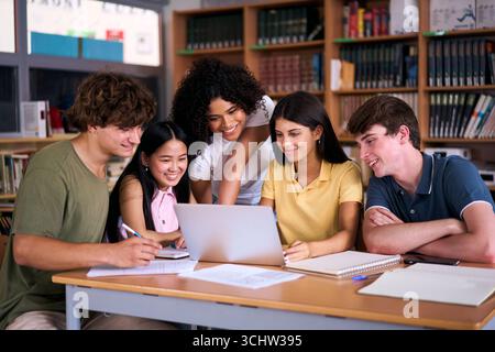 High school students collaborating on project in library using laptop Stock Photo