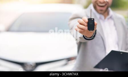 Businessman in suit showing or giving car key for customer getting new auto Stock Photo